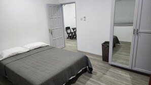 A bedroom with a bed, a wardrobe, a door, and a chair in the background. - Steps away from a beach & local transportation. Cozy one bedroom apartment (Saint George's)