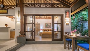 A room with a bed, a dining table with chairs, a kitchen area, and a decorative wall with plants. - Frida Villa Ubud by Best Deals Asia Hospitality (Ubud)