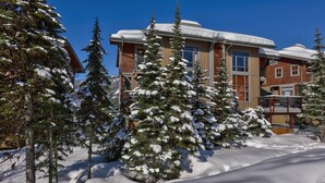 A snow-covered building with a modern design, surrounded by snow-laden trees. - Bright, Ski-in/Ski-out Townhouse with A/C (Sun Peaks)
