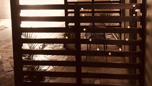 A covered outdoor seating area with string lights, wooden railings, and potted plants. - Apartment - Walk to the Beach (Lucea)
