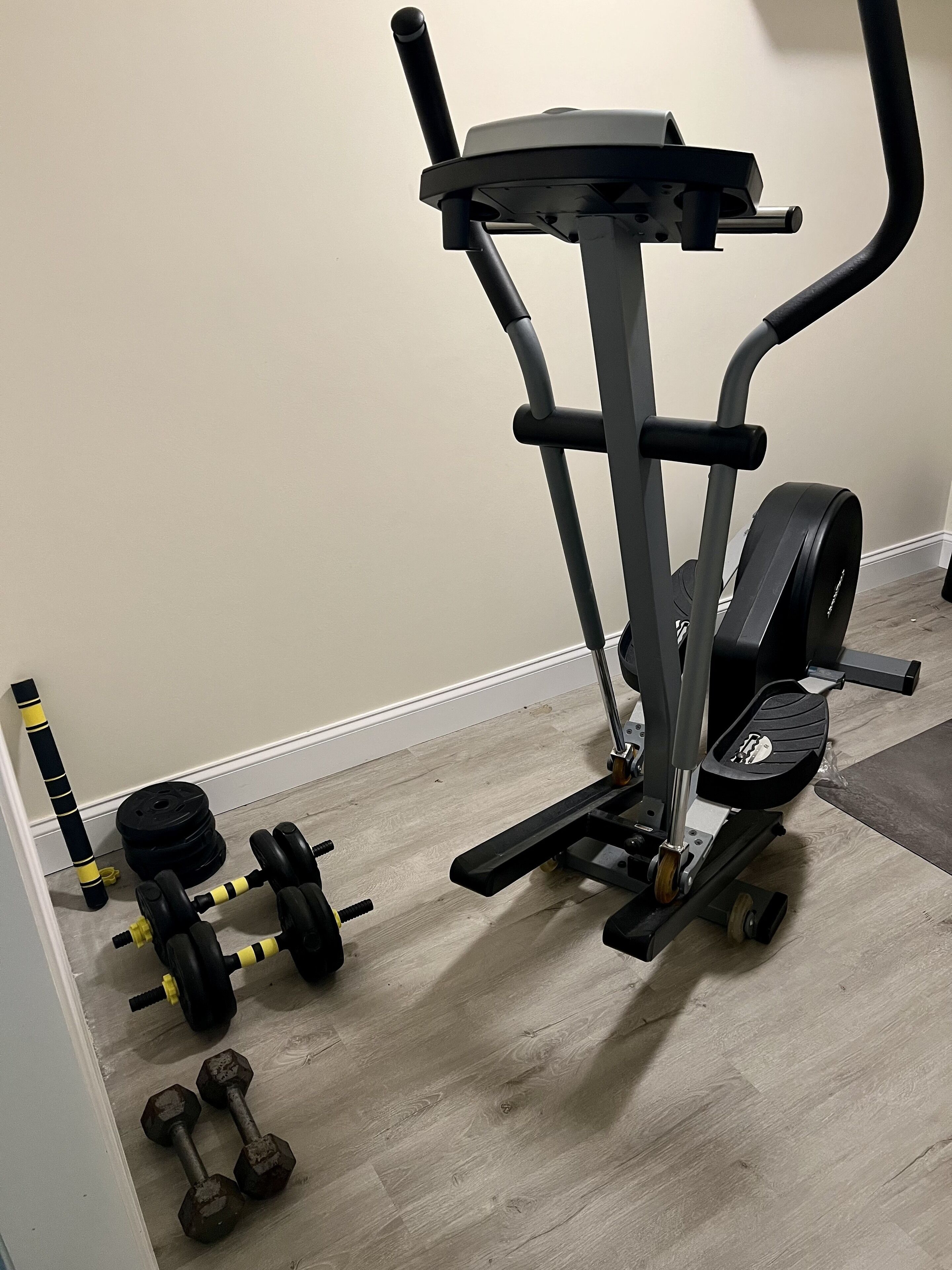 Un gimnasio en casa con una bicicleta estática, mancuernas y discos de pesas.