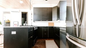 A modern kitchen with dark cabinetry, stainless steel appliances, and a wooden ceiling. - Modern Shipping Container Guest House w/ City Views (Denver)