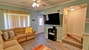 A living room with a sofa, a TV, and a staircase.