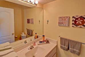 Une salle de bain avec un grand miroir, un lavabo et des serviettes. Les murs sont décorés avec des motifs et des inscriptions, et il y a un porte-serviettes.