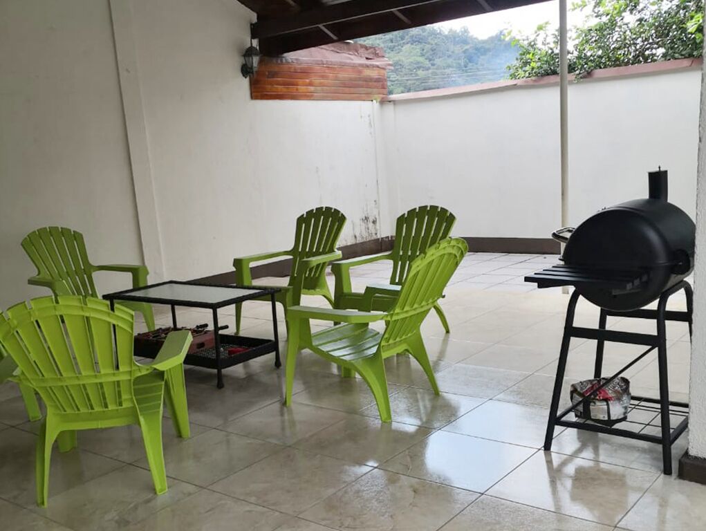 A patio with green chairs and a black grill.