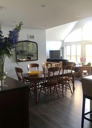 Enjoy meals around a spacious round table with comfortable seating for six, surrounded by a modern kitchen and large windows.