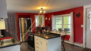 Une cuisine dotée d’un îlot central, d’appareils électroménagers en acier inoxydable et d’un mur d’accent rouge.