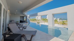 Ein moderner Poolbereich mit Liegestühlen und Blick auf den Ozean.