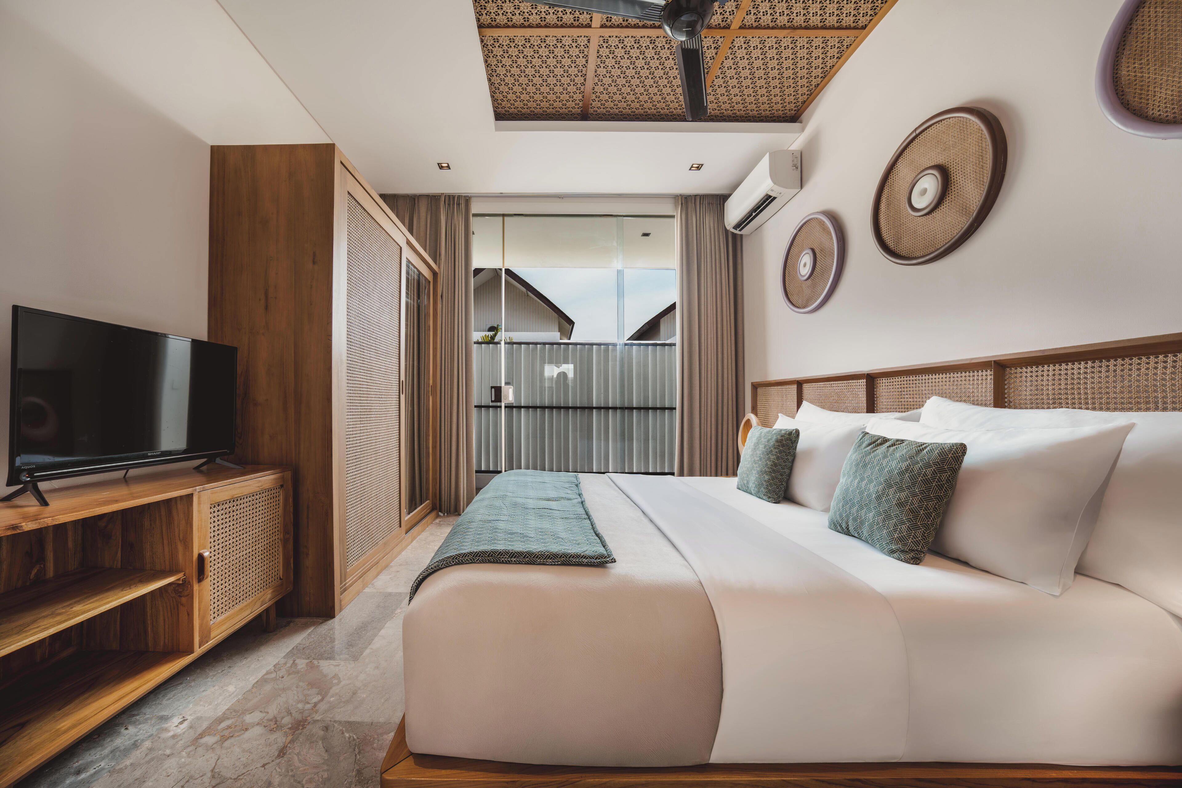 A modern hotel room with a large bed, a TV, and a balcony with a view.