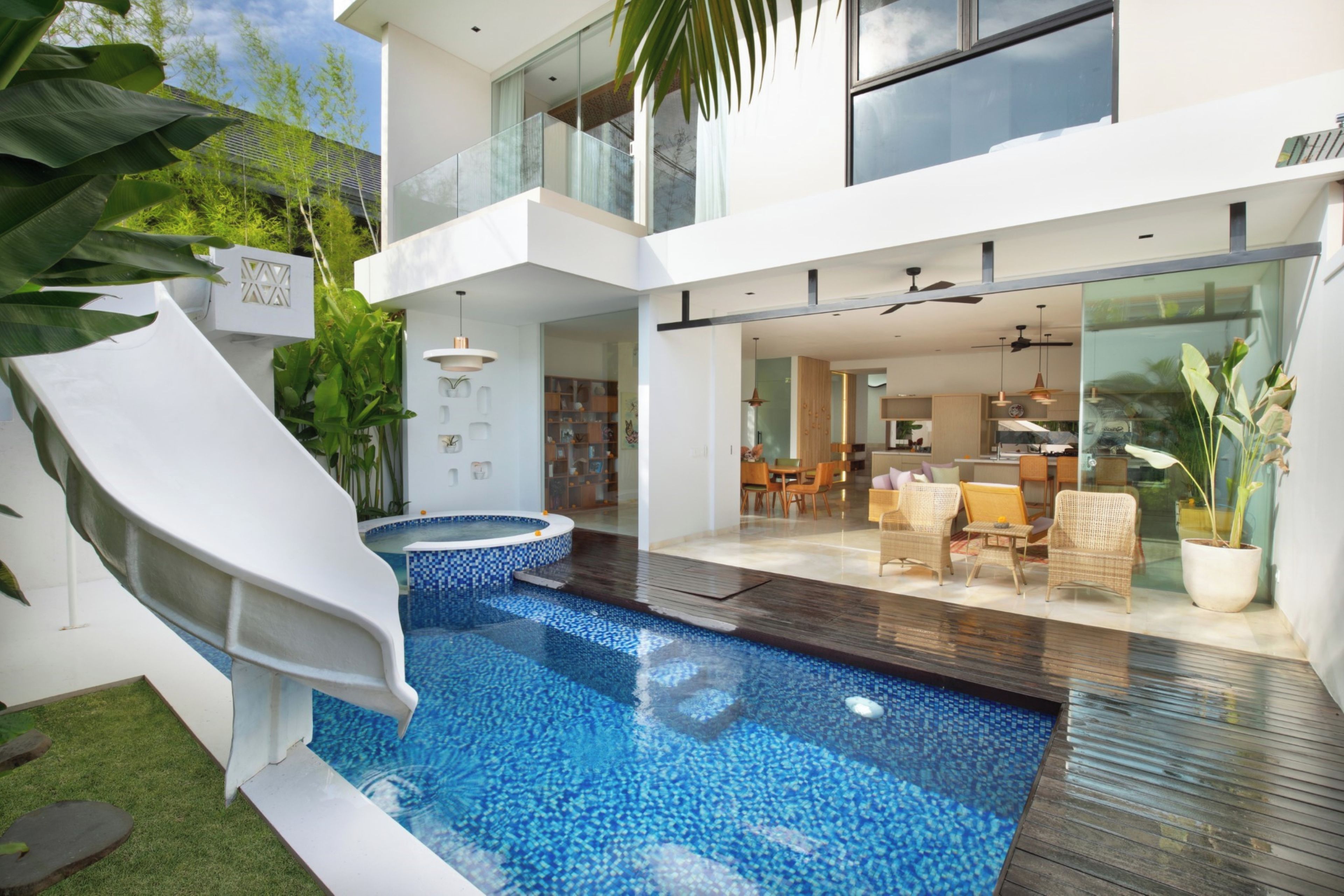 A modern house with a swimming pool, a slide, and a dining area.