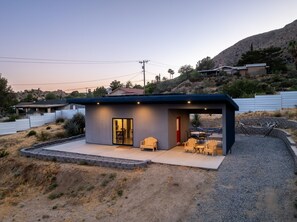 Une maison moderne dotée d’un patio, d’un espace salon extérieur et offrant une vue sur le paysage environnant.