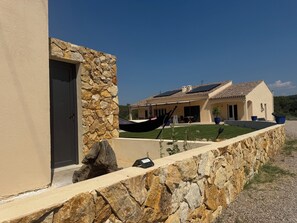A stone wall with a hammock, a stone door, and a house with a tiled roof. - Provençal farmhouse for 12 people · 10x5 pool · 6 bedrooms/6 bathrooms · Air conditioning (Lorgues)