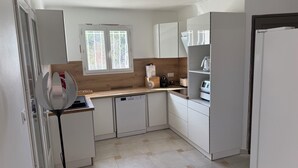 A compact kitchen with white cabinets, a dishwasher, a coffee maker, and a window with a view of trees. - Provençal farmhouse for 12 people · 10x5 pool · 6 bedrooms/6 bathrooms · Air conditioning (Lorgues)