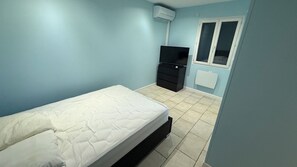 A bedroom with a bed, a dresser, a television, and a window.