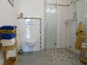 Ein Badezimmer mit Toilette, einer Duschkabine und einem Handtuchhalter mit Handtüchern.