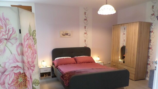 Ein Schlafzimmer mit einem Bett, Nachttischen, einem Kleiderschrank und einer Blumenwand.