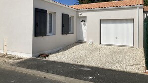 Un bâtiment à deux étages, à l’extérieur blanc, avec un toit recouvert de tuiles et une allée gravillonnée.