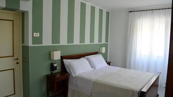 Een hotelkamer met een bed, nachtkastjes, een telefoon en een raam met gordijnen.