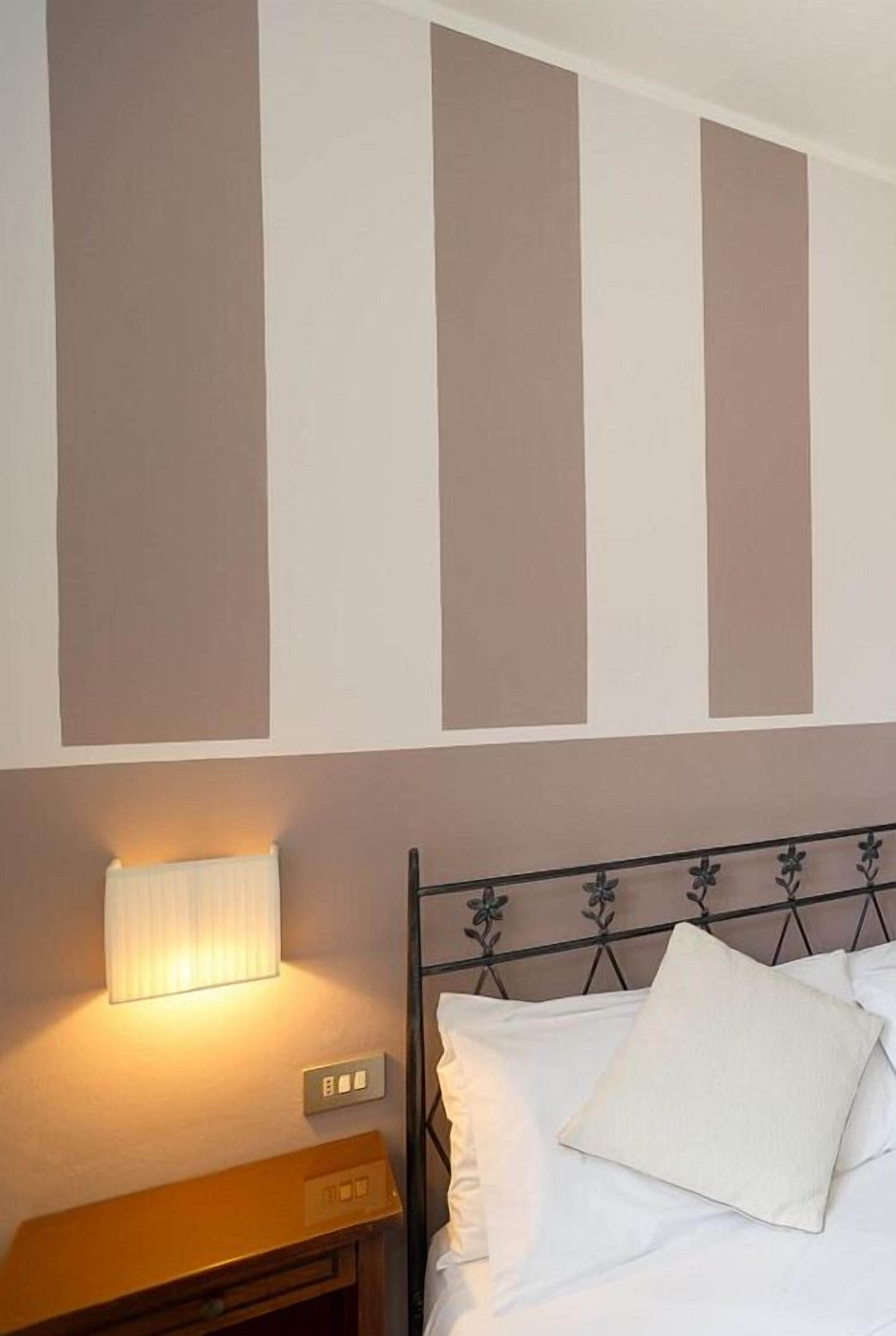 Un dormitorio con cama, una lámpara de noche y un aplique de pared.