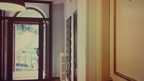 Um corredor interno com uma porta que dá para uma varanda.