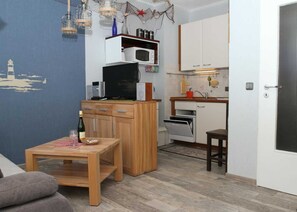 Un espacio habitable compacto con kitchenette, comedor y zona de estar.