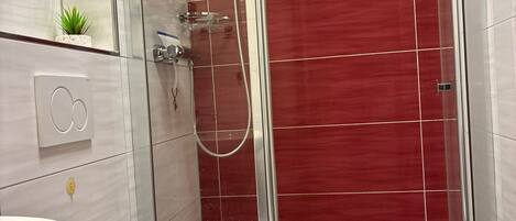 Un baño moderno con ducha acristalada, inodoro blanco y lavabo.