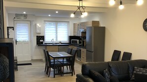 Eine moderne Küche mit Essbereich, einer schwarzen Ledersofa und Holzboden.
