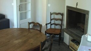 A dining area with a wooden table and chairs, a fireplace, and a door leading to another room. - Quiet house between ocean and Bassin d'Arcachon (Cap-Ferret)