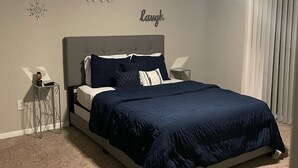 Een slaapkamer met een bed, een plafondventilator en decoratieve muurkunst.