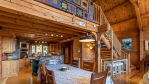 A wooden cabin interior with a dining area, kitchen, and a staircase leading to a loft. - Beary Relaxing Cabin - Big views, two kitchens, hot tub, game table (Banner Elk)