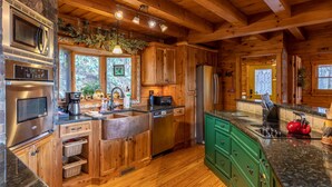 A wooden cabin kitchen with built-in appliances, a large island, and green cabinets. - Beary Relaxing Cabin - Big views, two kitchens, hot tub, game table (Banner Elk)