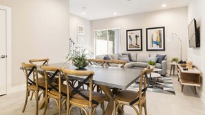 Ein modernes Wohnzimmer mit Essbereich, einer Sofagarnitur und zwei gerahmten Kunstwerken an der Wand.