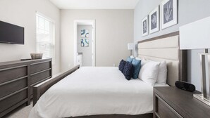Ein Schlafzimmer mit Bett, Kommode, Fernseher und Bildern an der Wand.