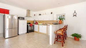 Een moderne keuken met roestvrijstalen apparatuur, witte kasten en een centraal kookeiland met zitplaatsen.