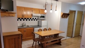 Una cocina con armarios de madera, un microondas, un lavabo y una mesa de comedor con sillas.