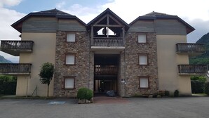 Un edificio con fachada de piedra, varios balcones y una entrada central.