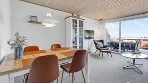 Ein moderner Besprechungsraum mit einem Holztisch, braunen Stühlen, einem großen Fenster und Blick ins Freie.