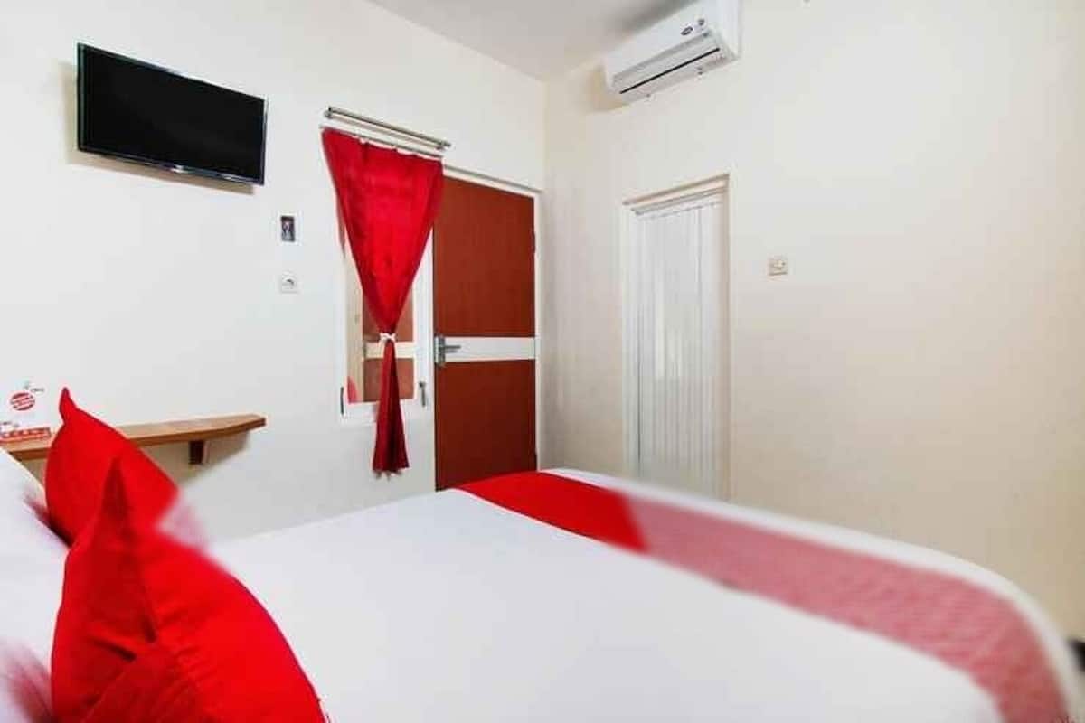 A hotel room with a bed, a TV, a wardrobe, and a door.