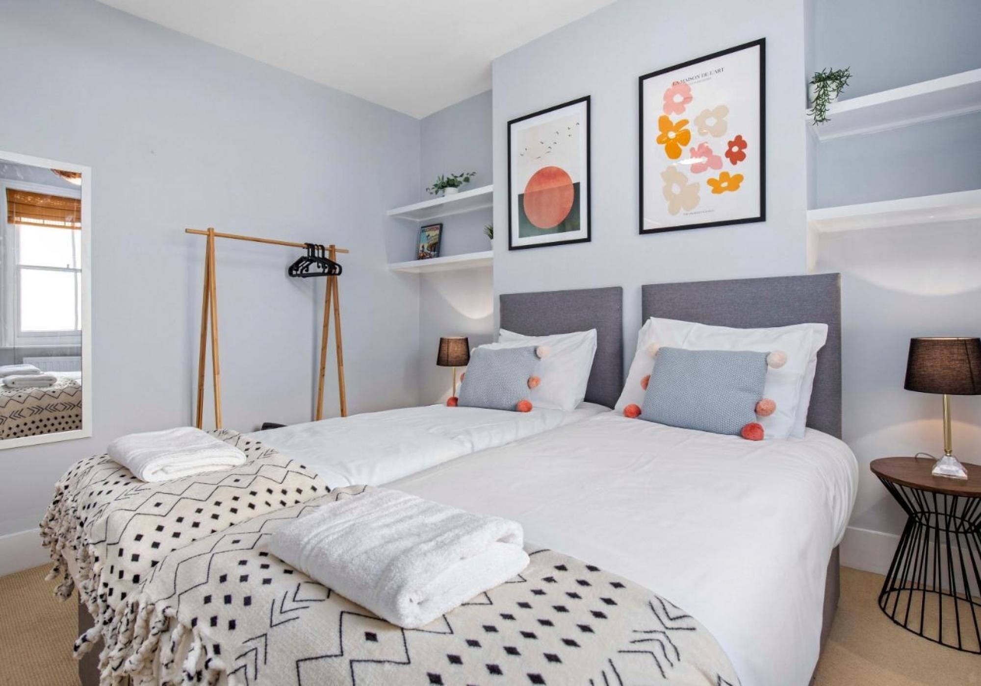 Una camera da letto moderna con un letto grande, due comodini, una rastrelliera appendiabiti e decorazioni alle pareti.
