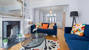 Ein Wohnzimmer mit Kamin, blauen Sofas und einem Glastisch.