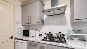 A modern kitchen with white cabinets, a gas stove, a microwave, and a dishwasher.