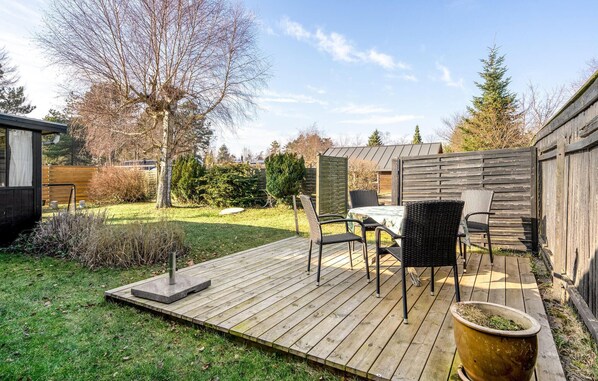 A wooden deck with outdoor furniture, a pergola, and a garden area with trees and shrubs. - 2 bedroom amazing home in Væggerløse (Væggerløse)