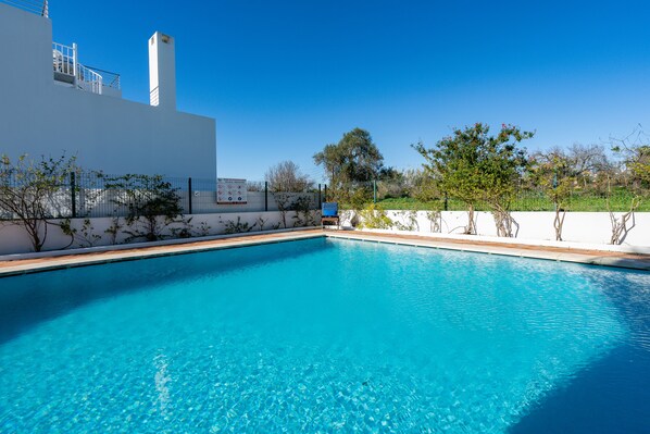 Une piscine d’un bleu éclatant, avec un bâtiment blanc en arrière-plan.