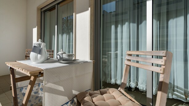 A balcony with a table, a chair, and a sofa.