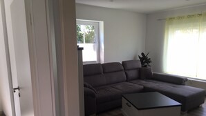 Una sala de estar con un sofá modular, una mesa de centro y una ventana con cortinas.