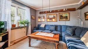 Un salon chaleureux avec un canapé bleu, une table basse en bois et des tableaux encadrés accrochés au mur.
