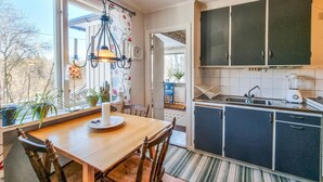 Une cuisine avec une table en bois, des chaises, un luminaire suspendu, un évier et des placards.