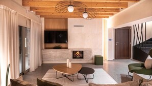 Una sala de estar moderna con chimenea, techo de madera y un sillón verde.