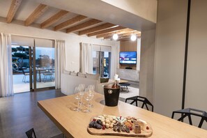 Enjoy a gourmet meal at this stylish room, featuring a dining table set with a variety of cheeses, fruits, and nuts, and a television for entertainment.