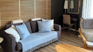 Un salón moderno con un sofá de color oscuro, una mesa de centro de madera y una silla.